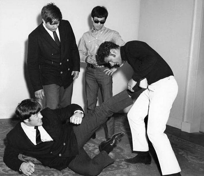 The Beatles, in a room, pose in a playful manner.