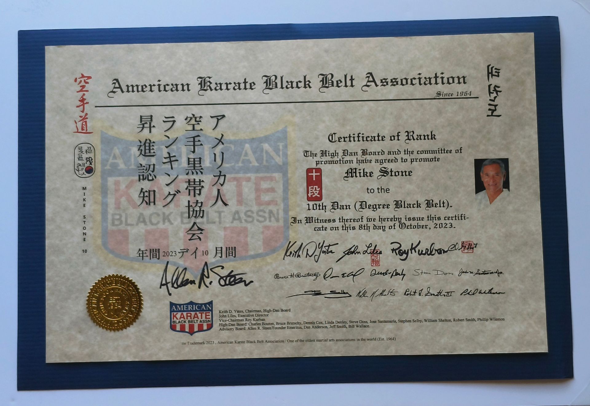 Karate certificate on blue mat. It features a gold seal, black text, and a photo of a man.