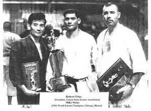 Winners of a karate tournament: three men holding trophies, standing side-by-side. They are in karate uniforms.