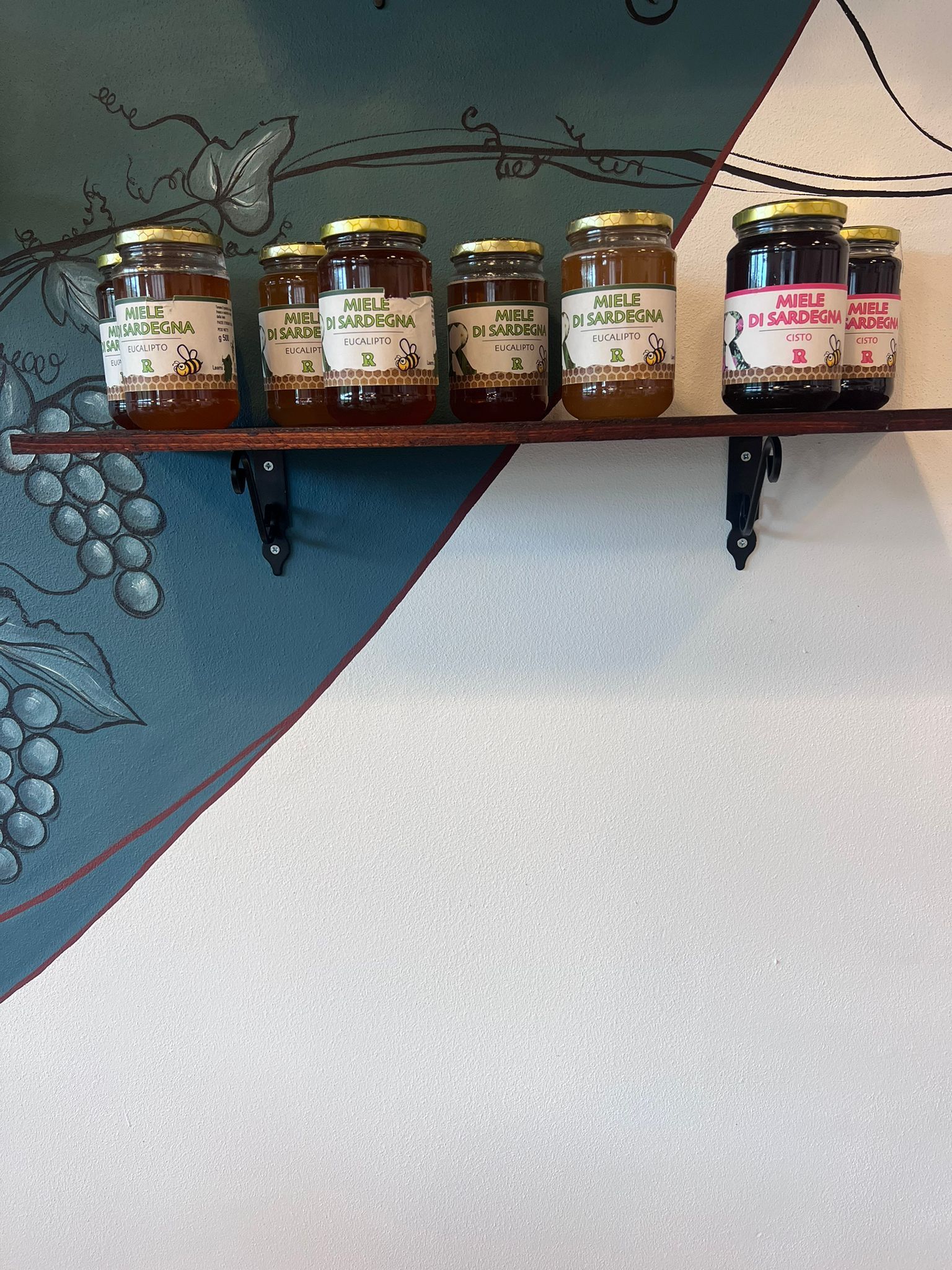Uno scaffale pieno di barattoli di marmellata e miele.