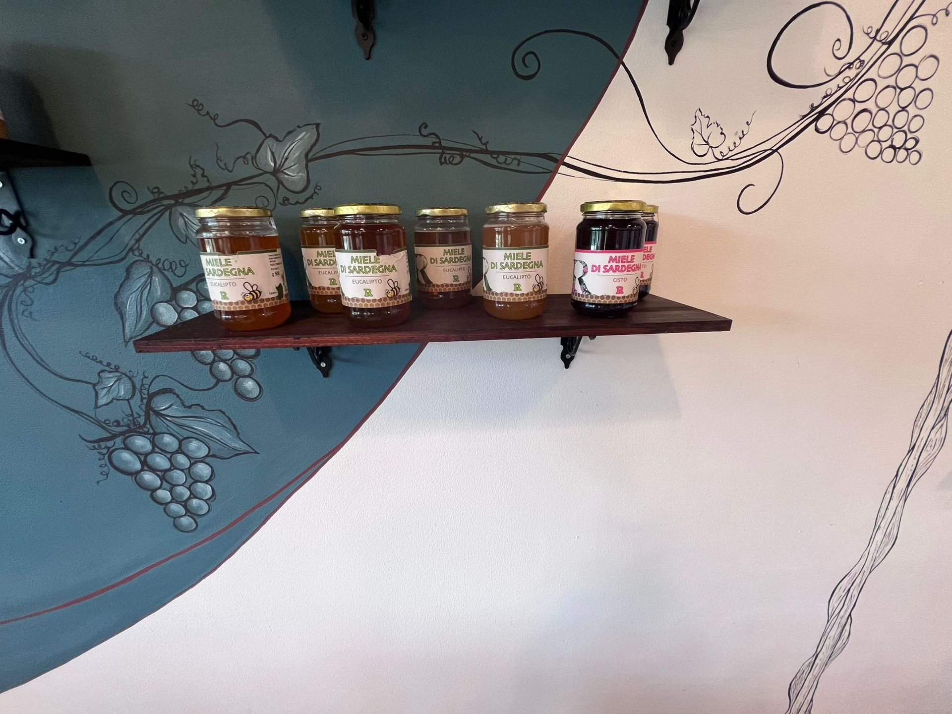 Uno scaffale con sopra barattoli di miele e marmellata