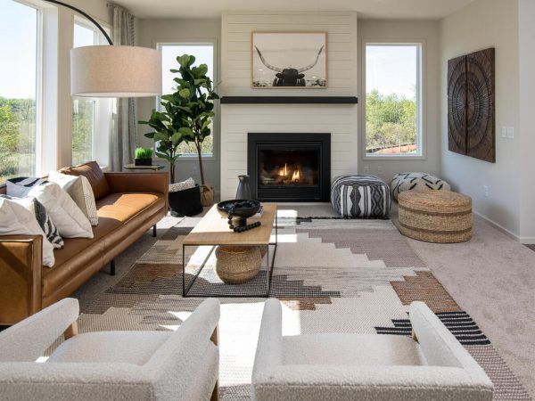 Living room with brown leather sofa, fireplace, area rug, and two white armchairs.