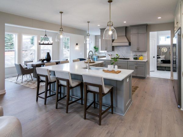 Modern kitchen with island, gray cabinets, white countertops, wood floor, and dining area.