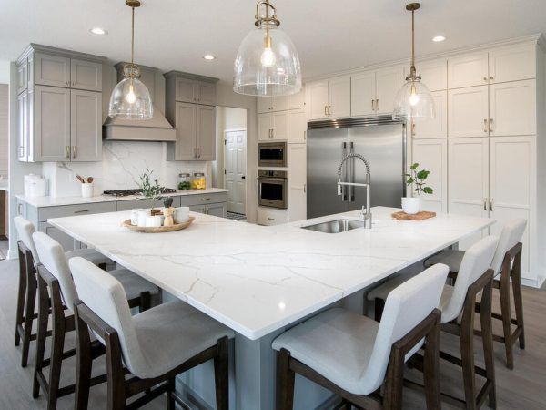 Modern kitchen with large island, white countertops, gray cabinets, and bar stools.