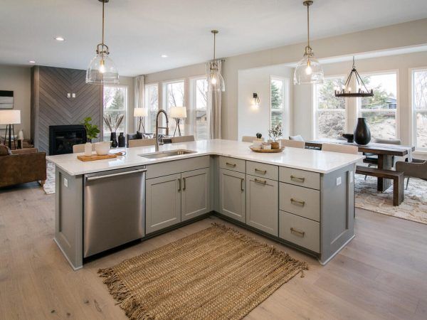 Modern kitchen with gray island, white countertops, stainless steel appliances, and hardwood floors.