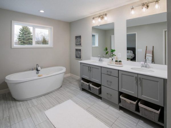 Modern bathroom with gray vanity, soaking tub, and large window overlooking greenery.