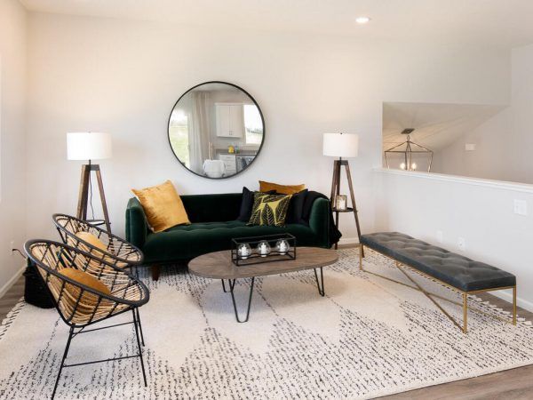 Living room with green sofa, round mirror, patterned rug, chairs, and bench.