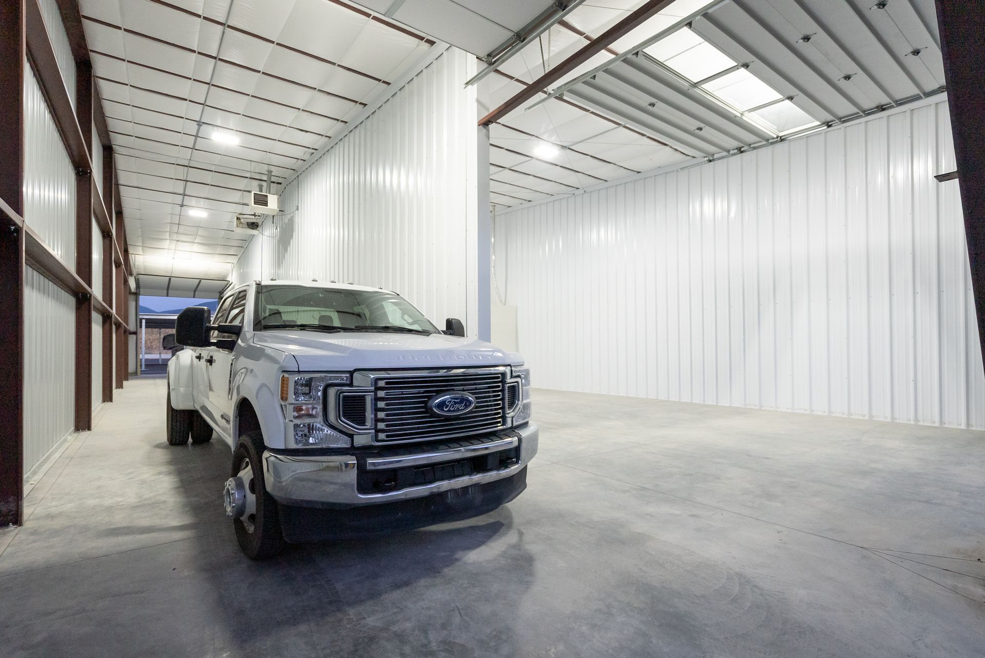 A white truck is parked in a garage with white walls.