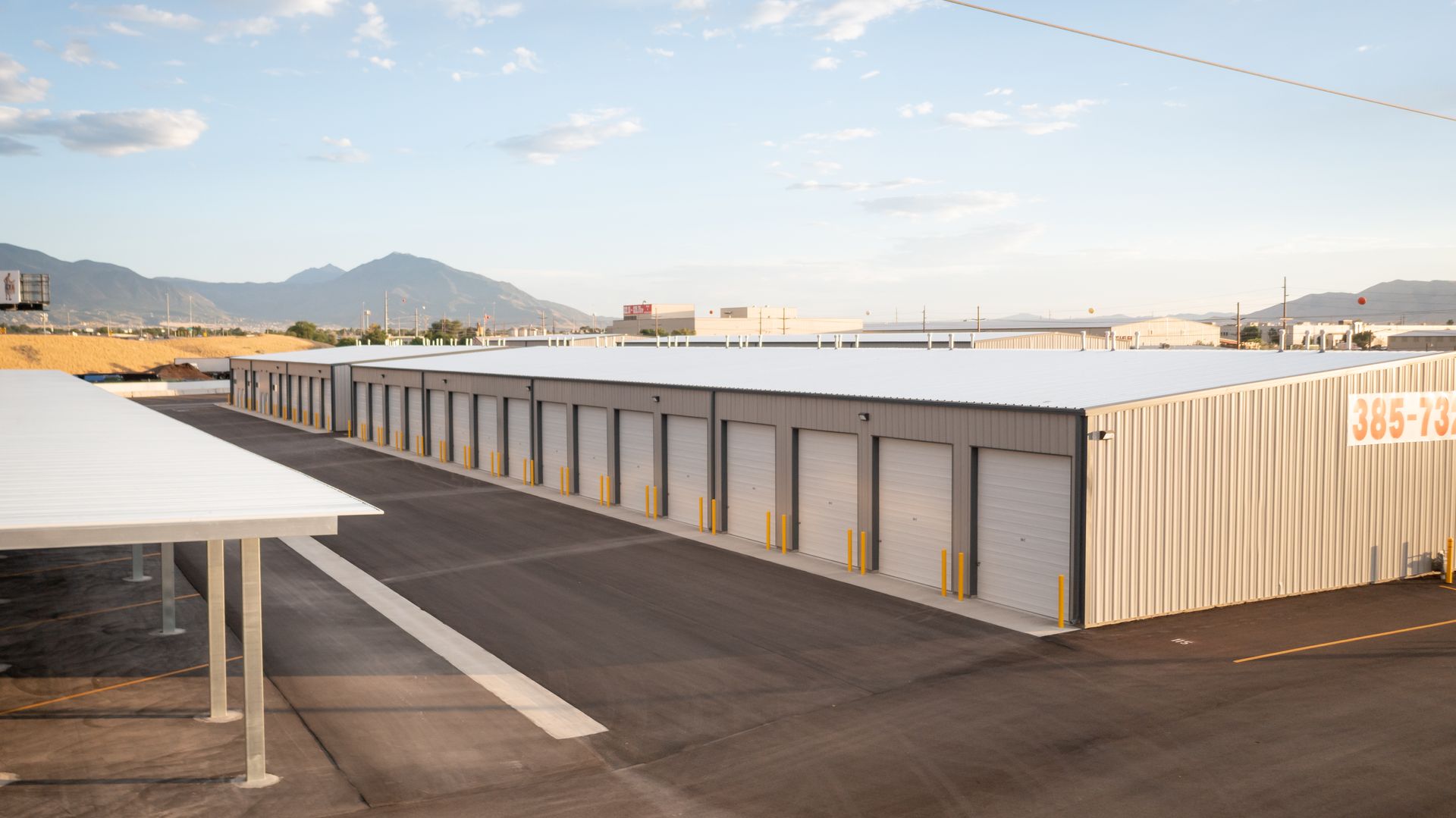 A row of storage units with a canopy and mountains in the background.