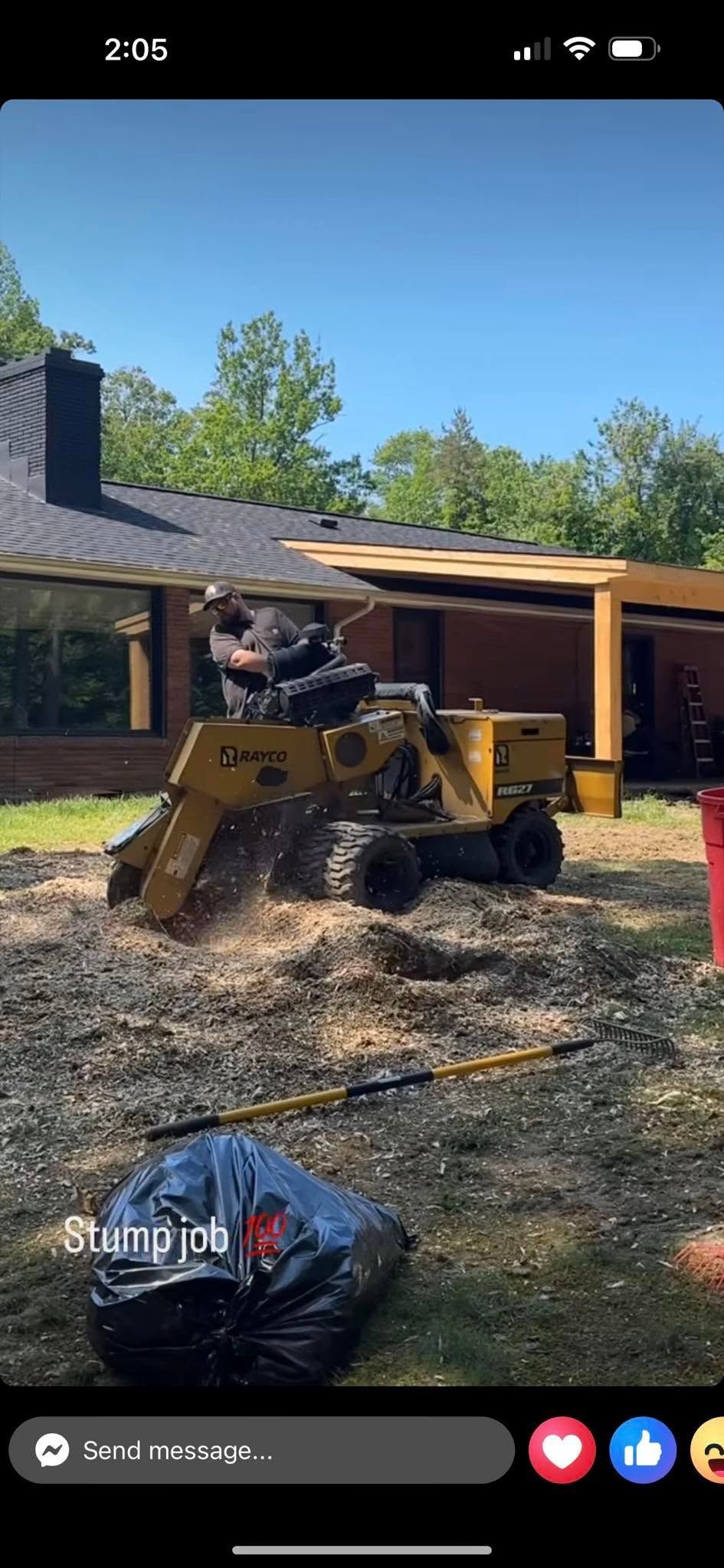 Yellow skid steer moving mulch in a driveway beside a house on a sunny day