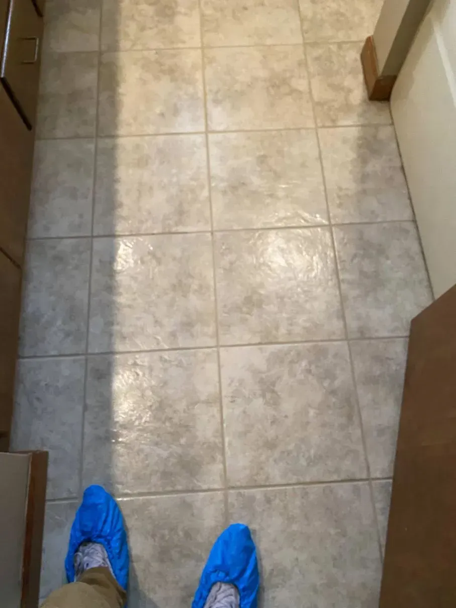 Person wearing blue shoe covers standing on tiled floor.