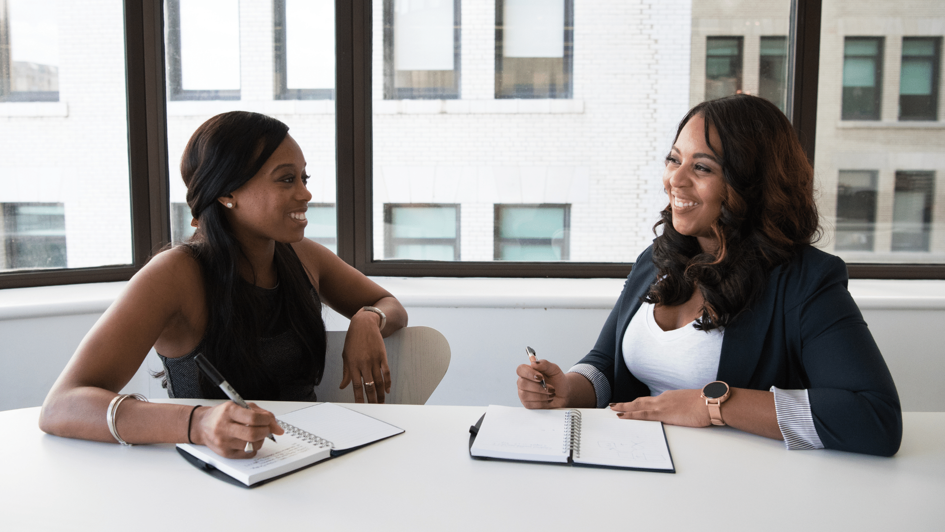Two women are sitting at a table having a conversation.