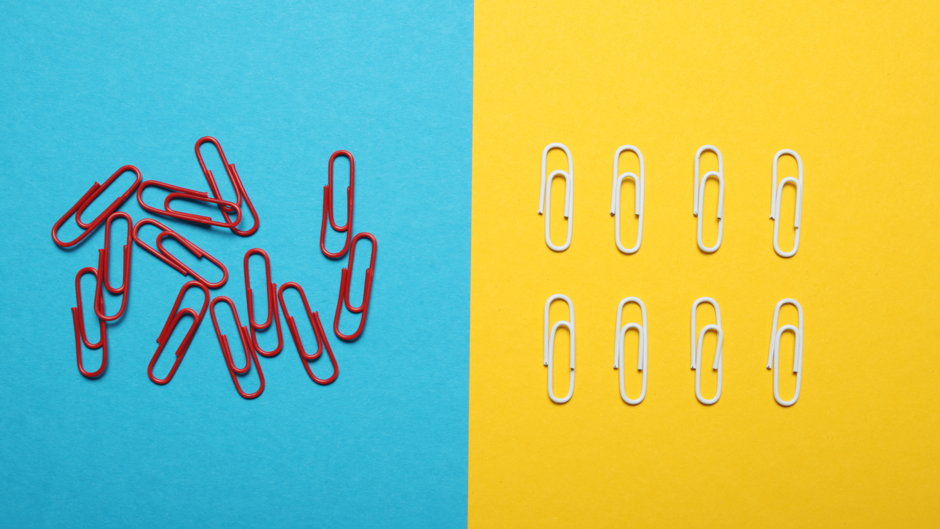 Red paper clips and silver paper clips on a blue and yellow background.