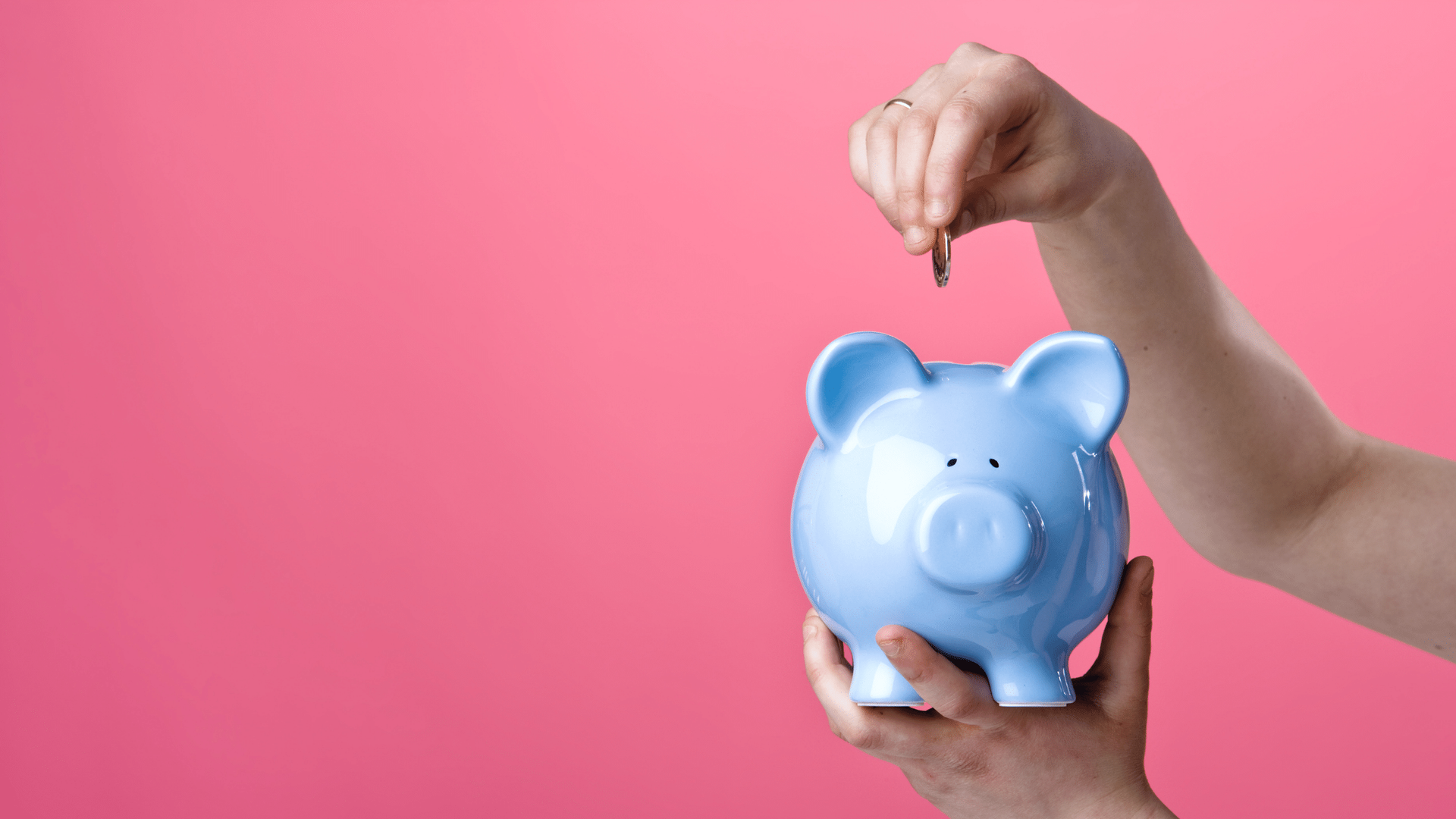 A person is putting a coin into a piggy bank.