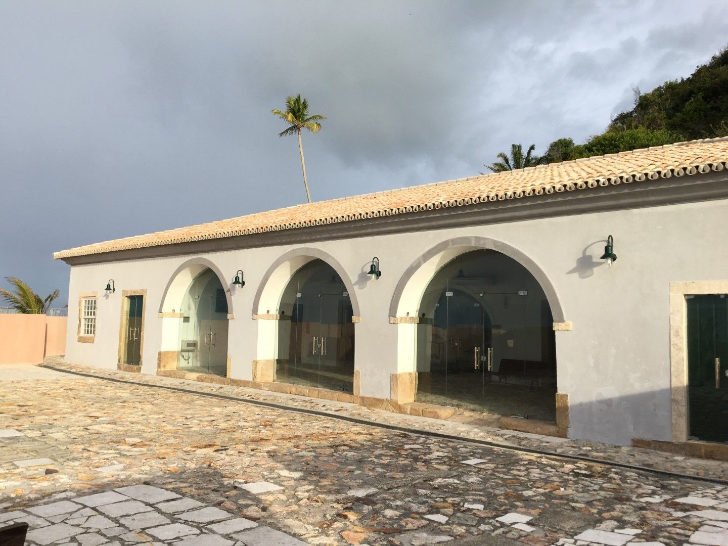 Área de recepção com paredes cor-de-rosa, balcão de madeira, cadeiras e piso de azulejo.