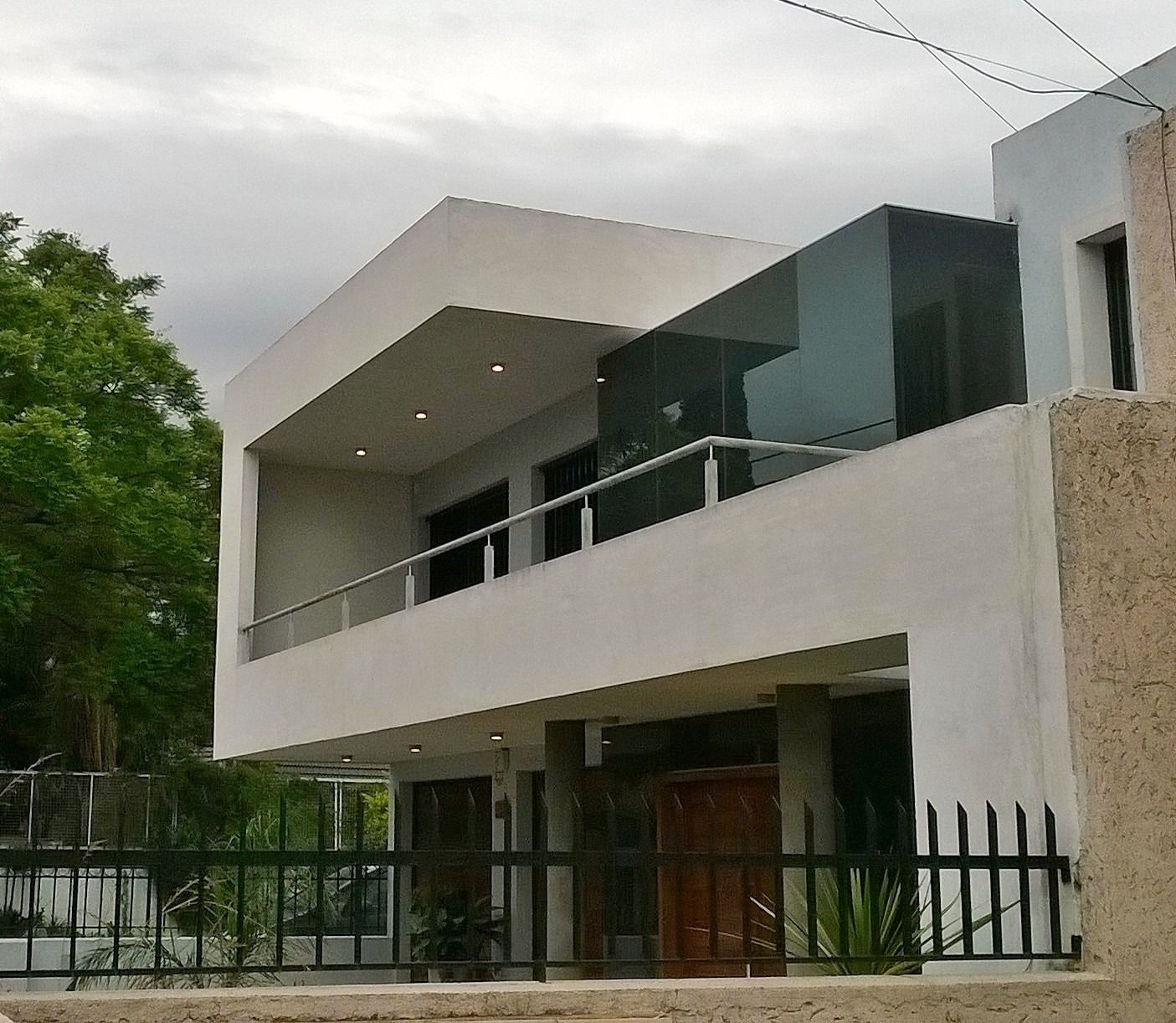 Casa moderna de dos plantas con revestimiento de madera, ventana grande y detalles blancos en un día soleado.