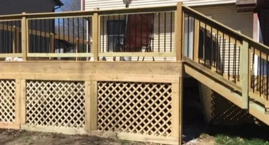 Wooden deck with railing, lattice skirting, and stairs leading down to a yard.