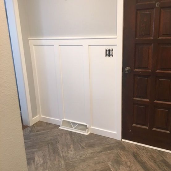 Hallway with white wainscoting, a dark wood door, and a floor vent by the wall