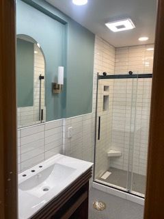 Modern bathroom with sink, mirror, shower stall, and blue and white tiled walls
