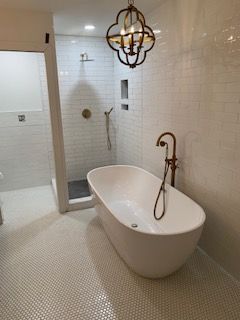 Elegant bathroom with freestanding tub, gold fixtures, tiled walls, and glass shower enclosure