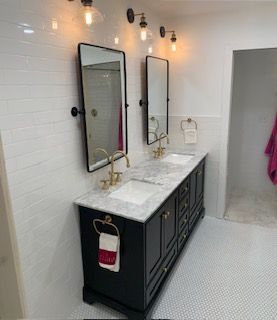 Modern bathroom vanity with double mirrors, marble countertop, black cabinet, and white tile walls.