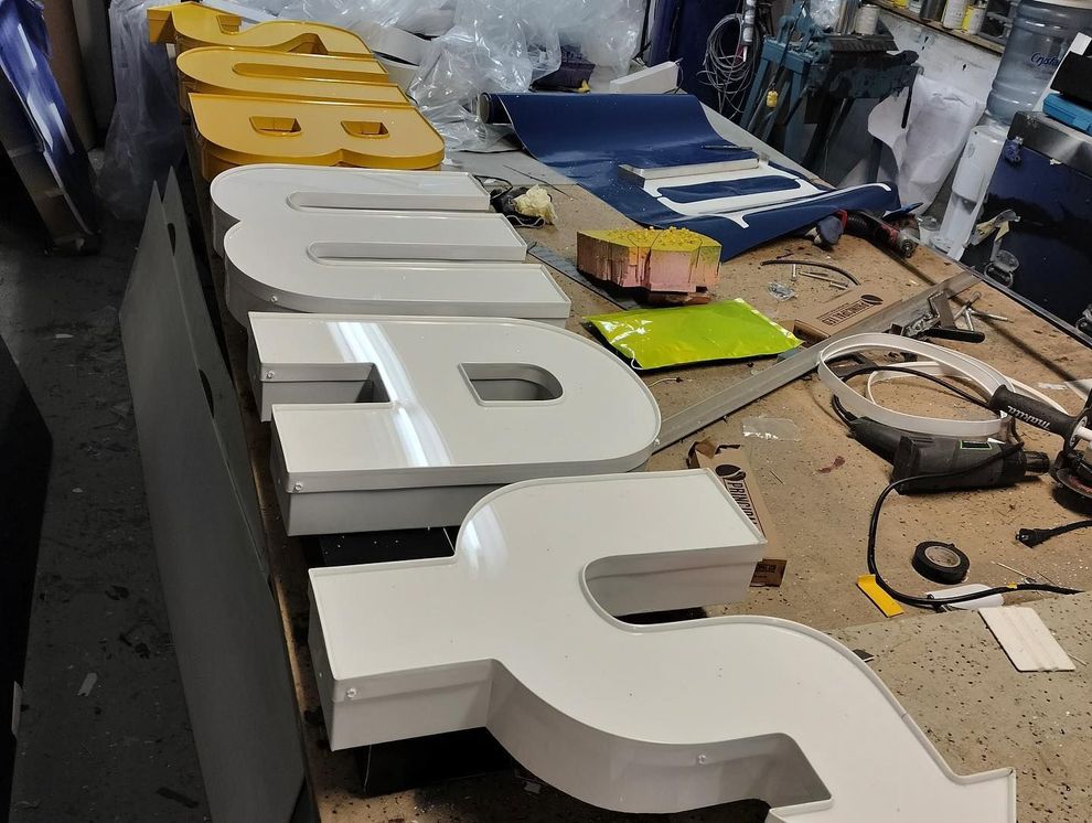 a row of letters sitting on top of a wooden table for a subway channel letter sign