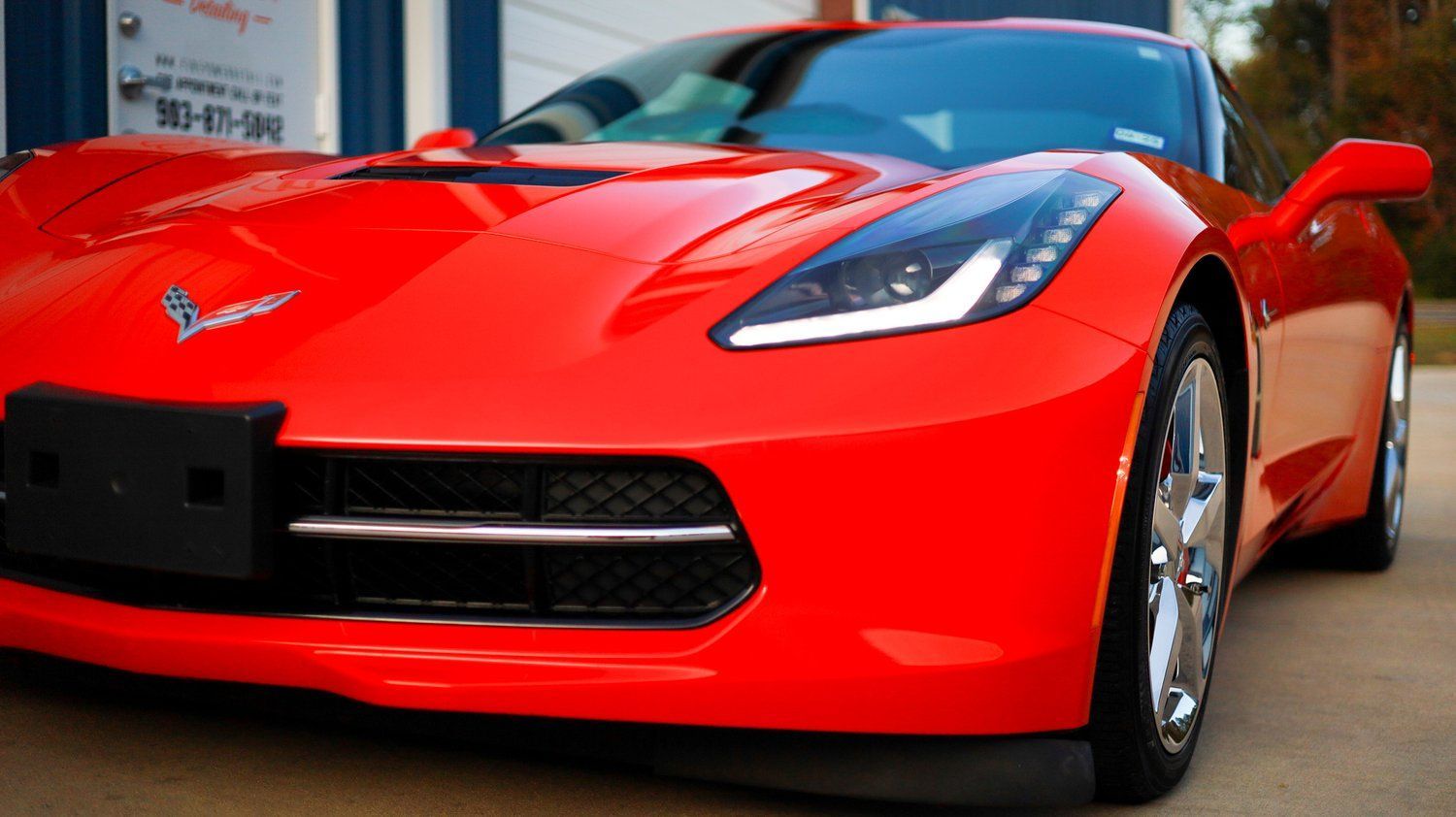 A red sports car is parked in front of a garage.