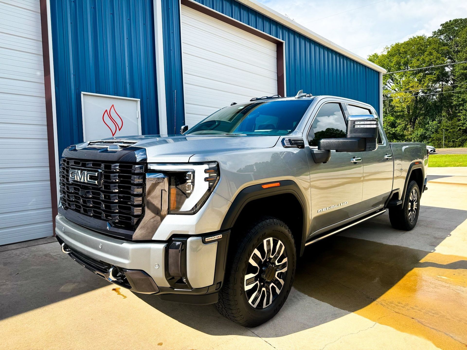 A silver truck is parked in front of a blue garage door.