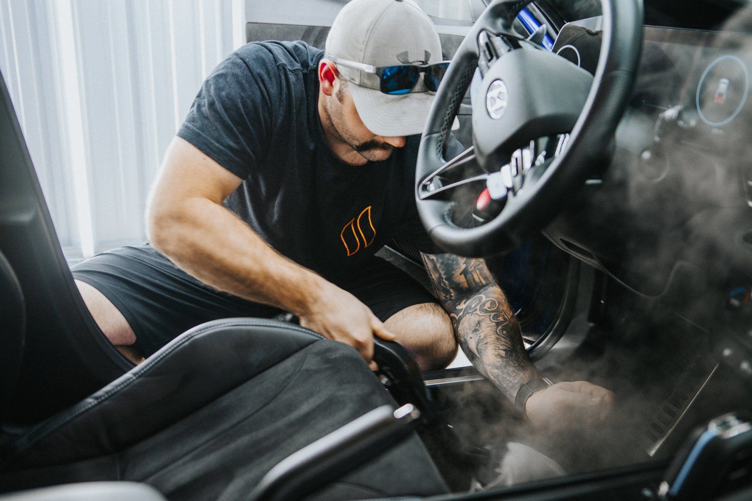 A man is cleaning the interior of a car with a vacuum cleaner.