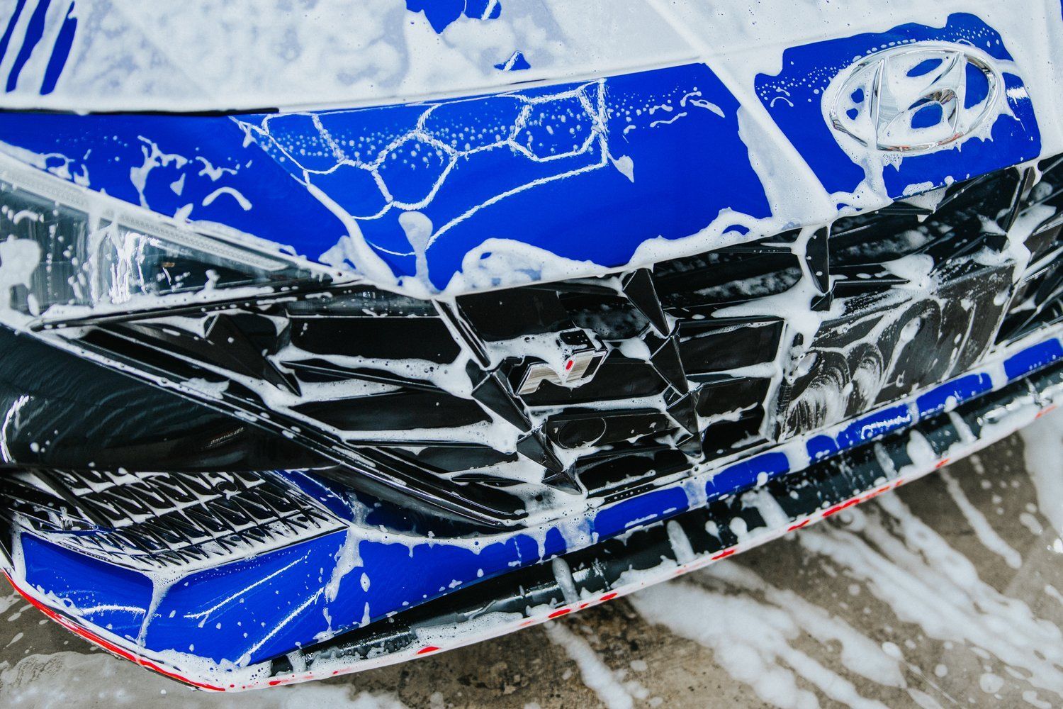 A blue and black car is covered in foam.