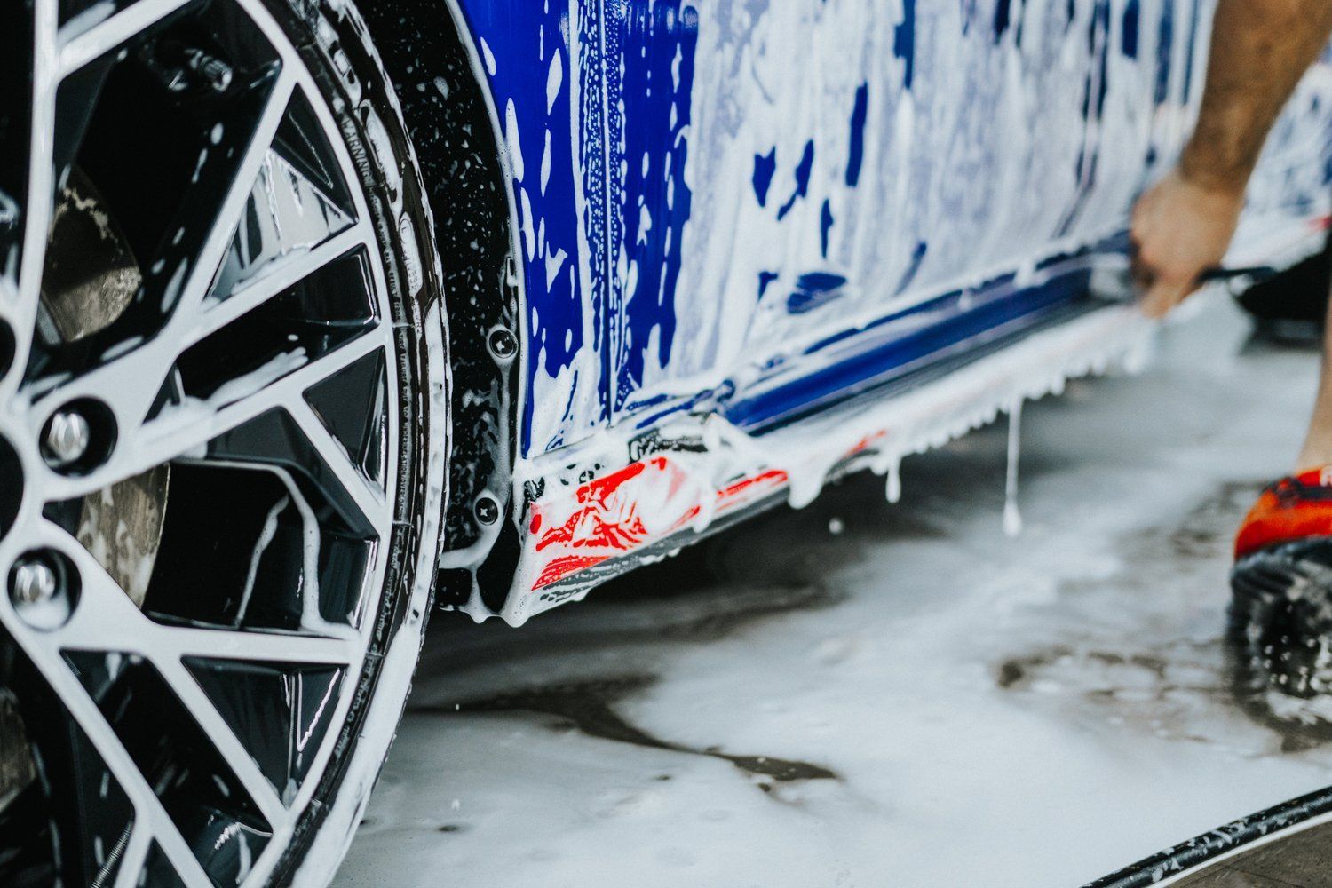 A person is washing a car with soap and water.