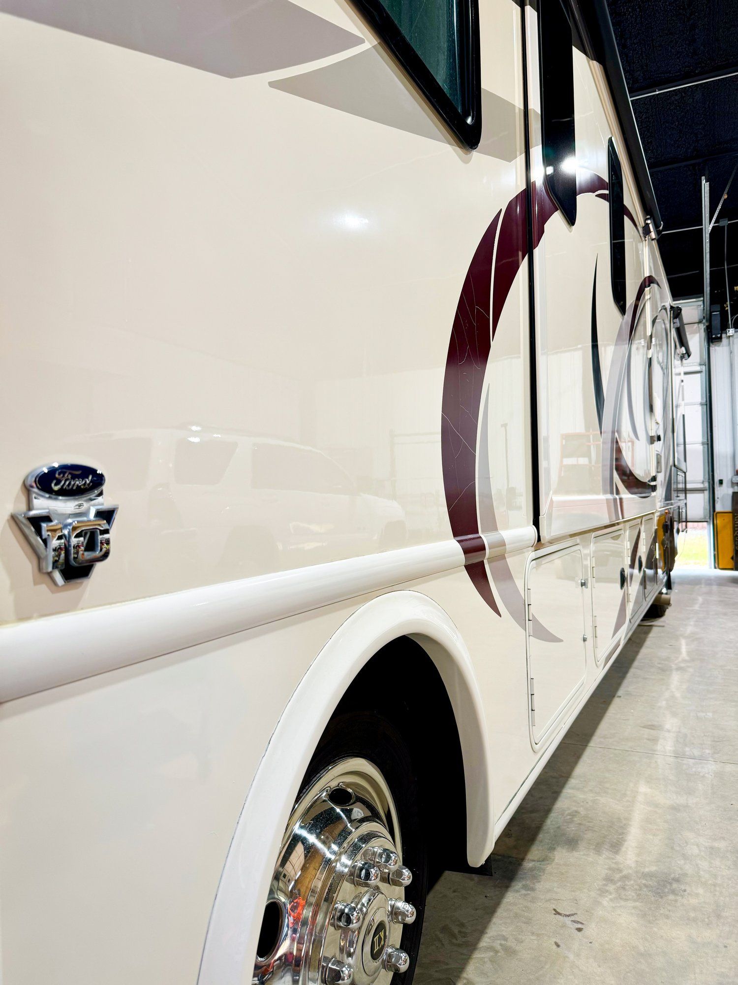 A white bus with a red circle on the side is parked in a garage.