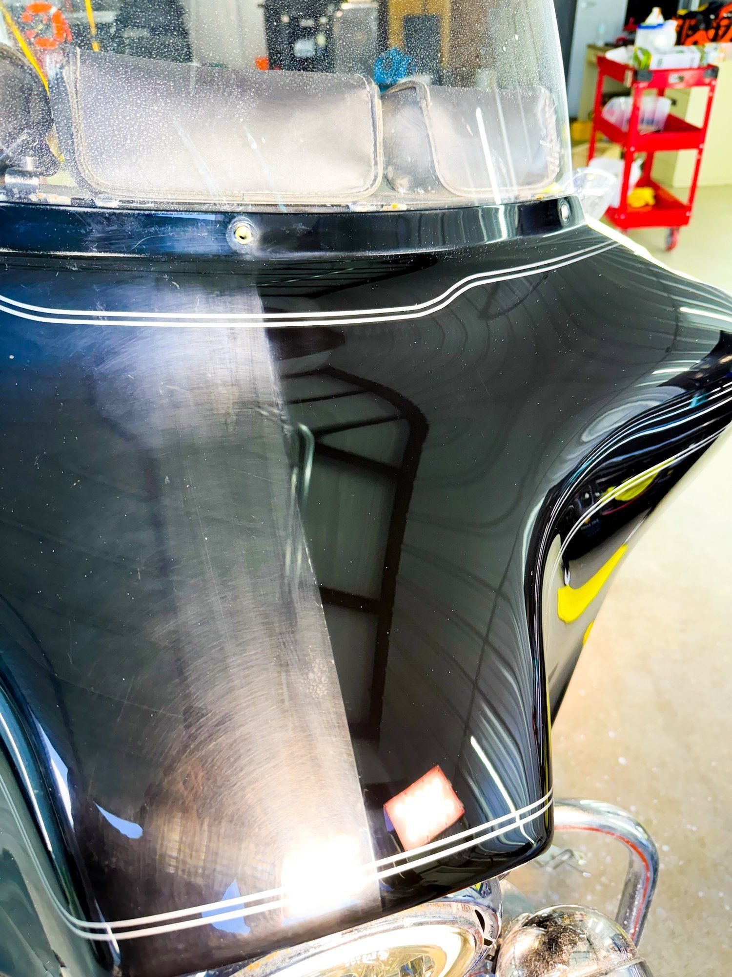A black motorcycle with a windshield is sitting in a garage.