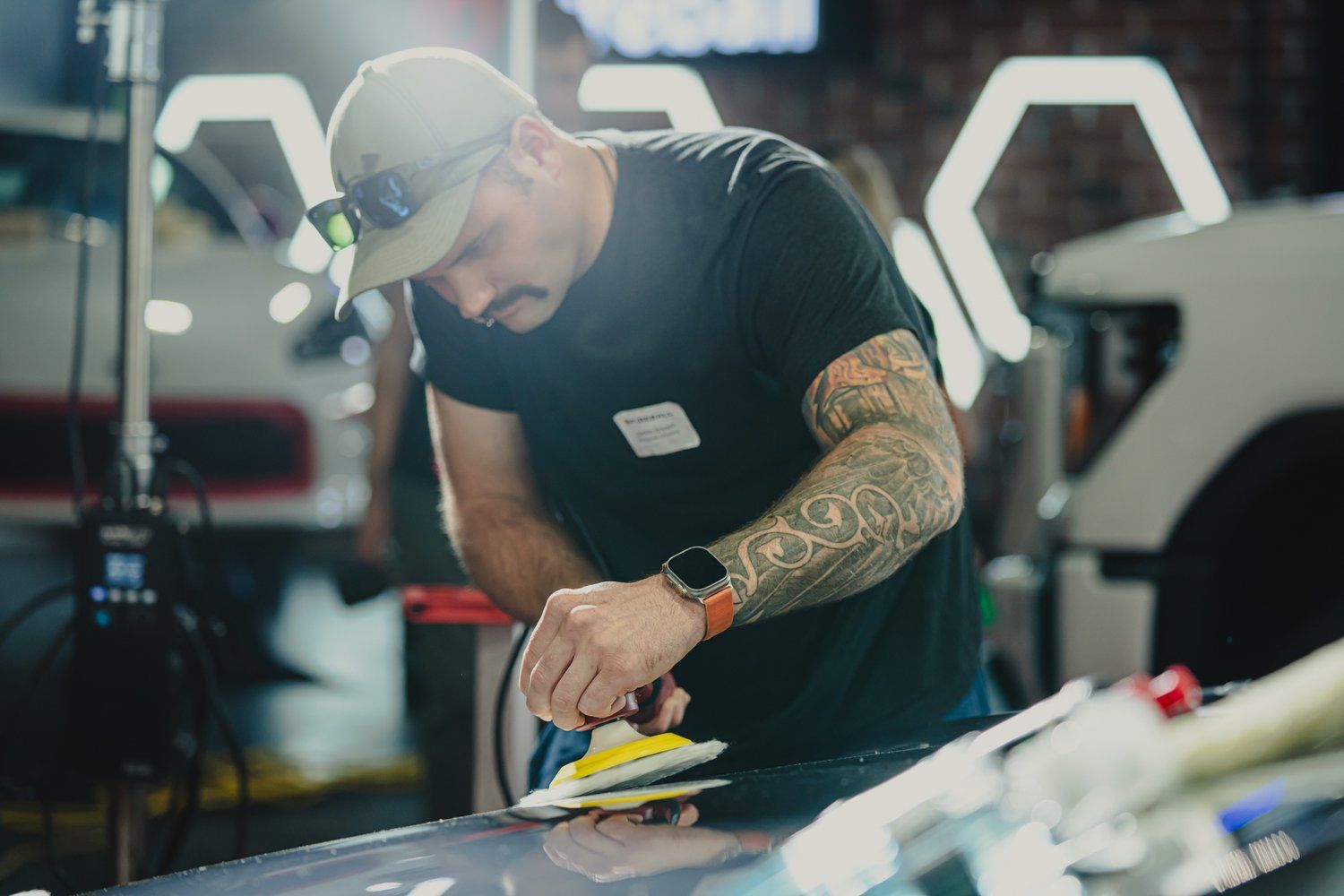 A man is polishing a car with a sander.