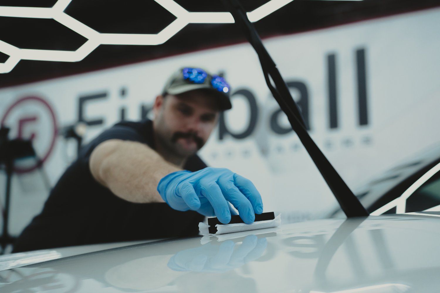 A man wearing blue gloves is working on a car