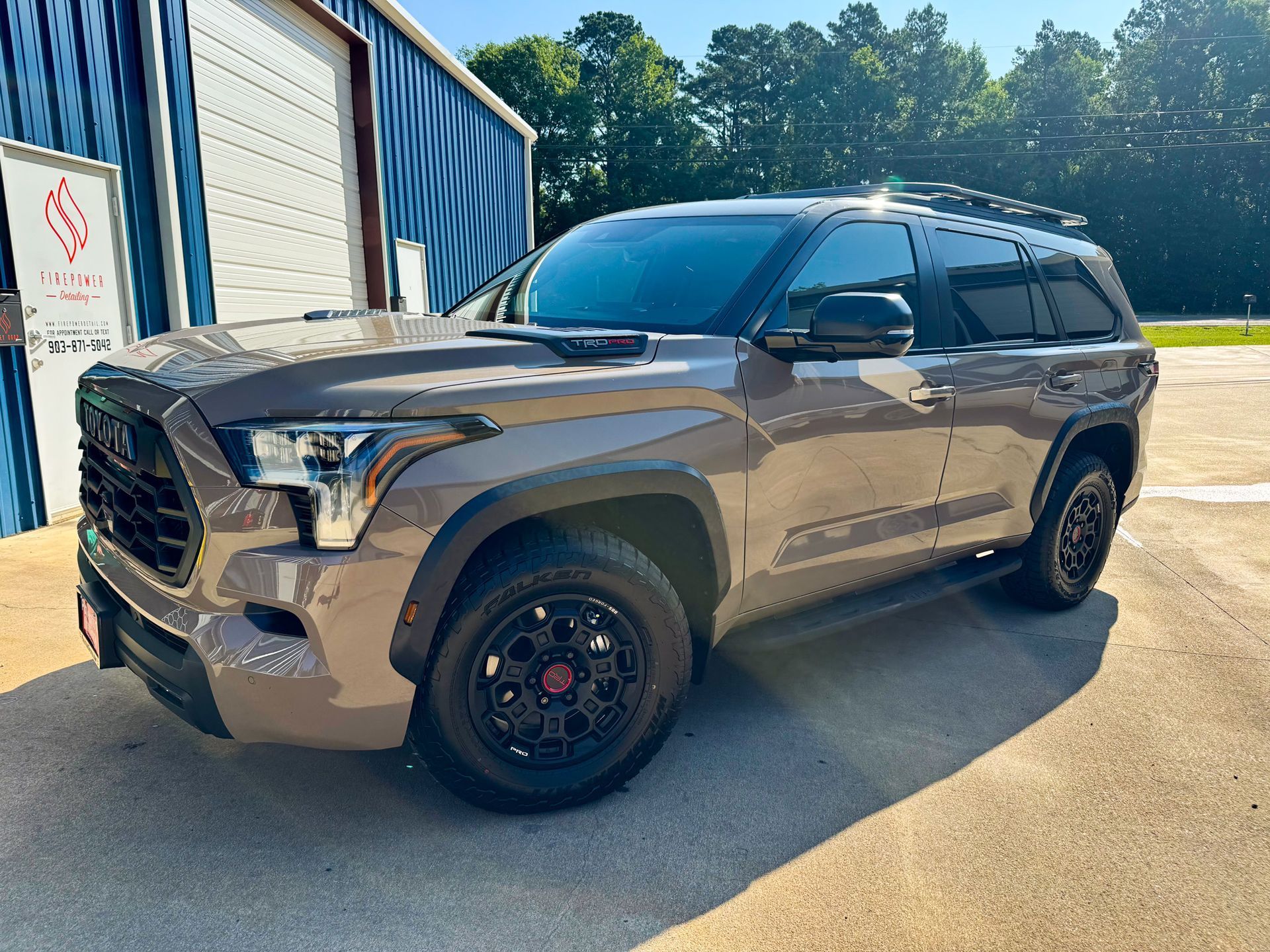 A black suv is parked in front of a blue building.