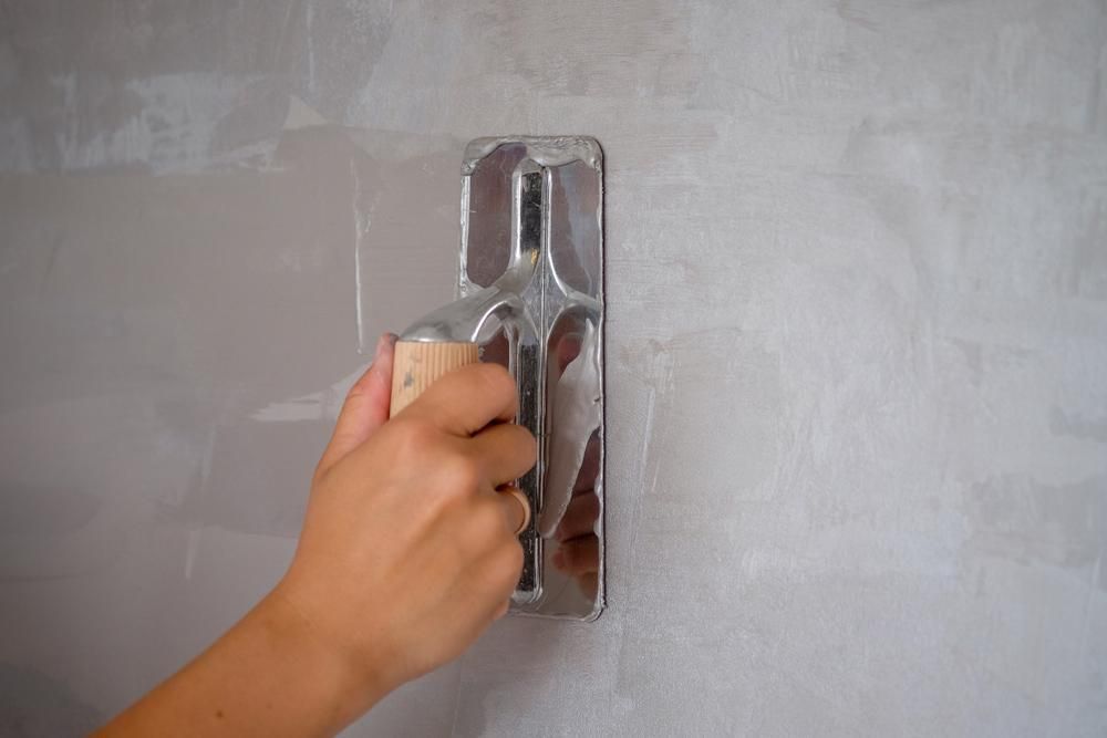 A Person Is Plastering A Wall With A Trowel — Donnelly Painting In Wollongbar, NSW