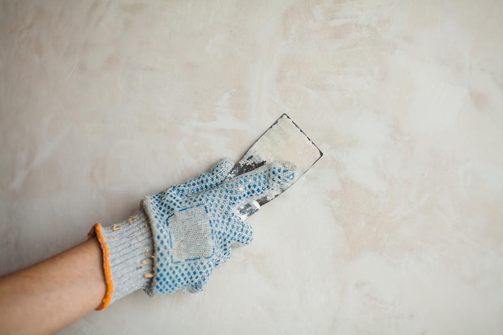 A Person Is Holding A Plaster Tool In Their Hand — Donnelly Painting In Wollongbar, NSW