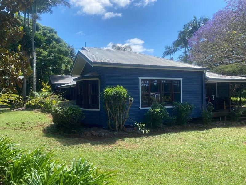 A Small Blue House Is Sitting In The Middle Of A Lush Green Field — Donnelly Painting In Wollongbar, NSW