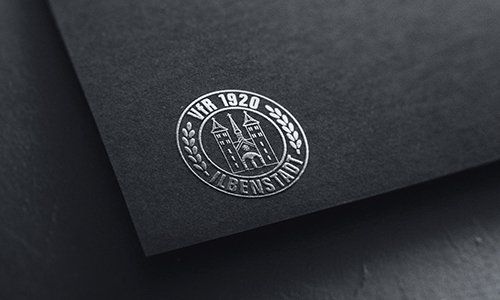 Ein schwarzes Stück Papier mit einem silbernen Logo darauf.