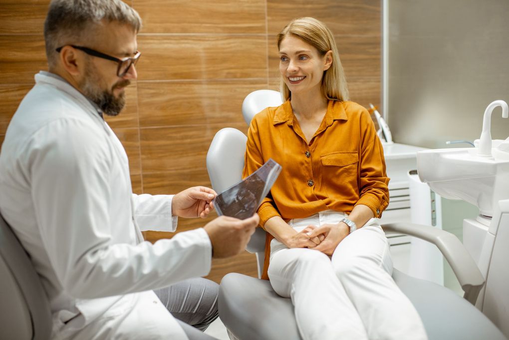 A dentist is talking to a patient in a dental chair.