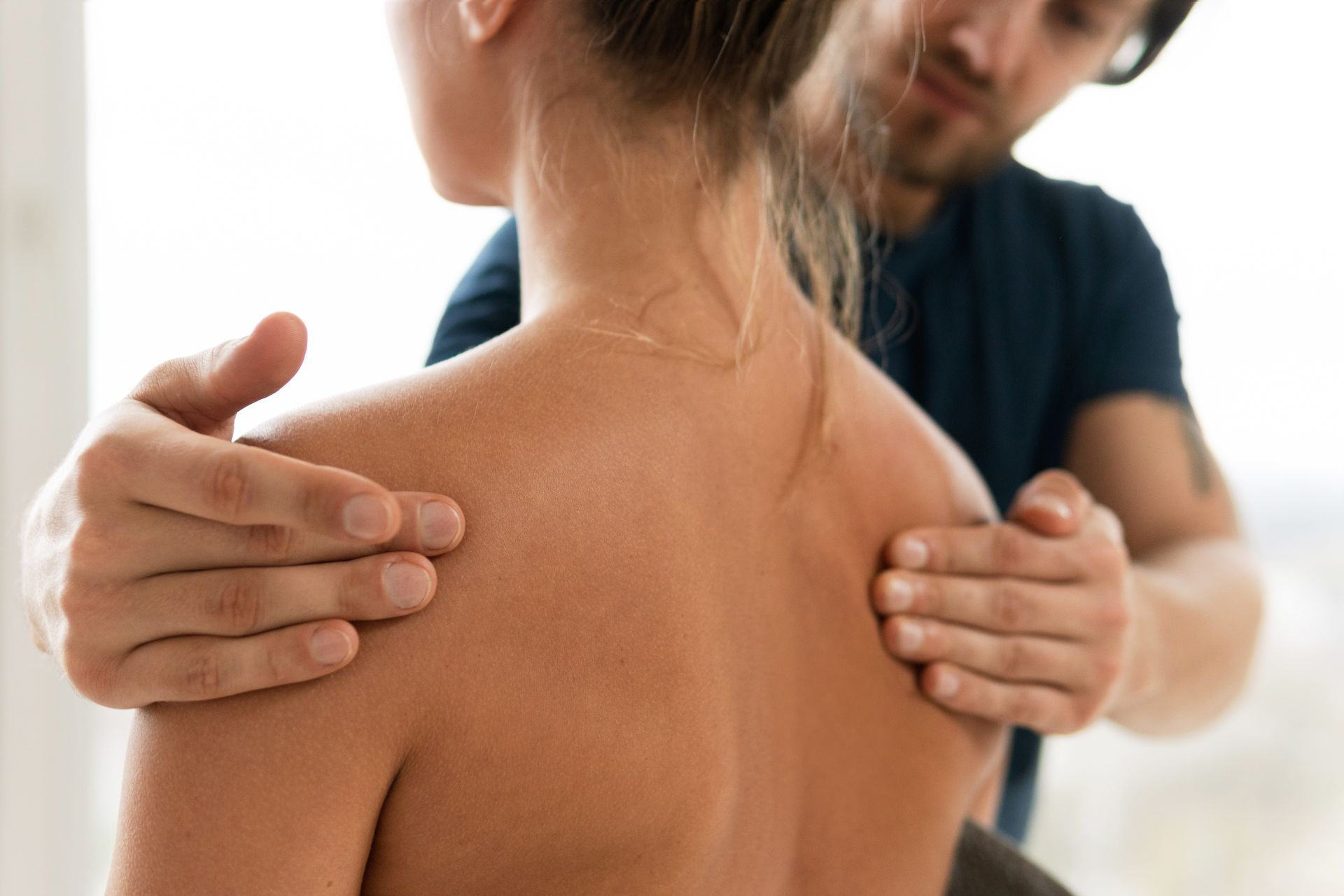 Physical therapist massaging a patient's upper back during treatment