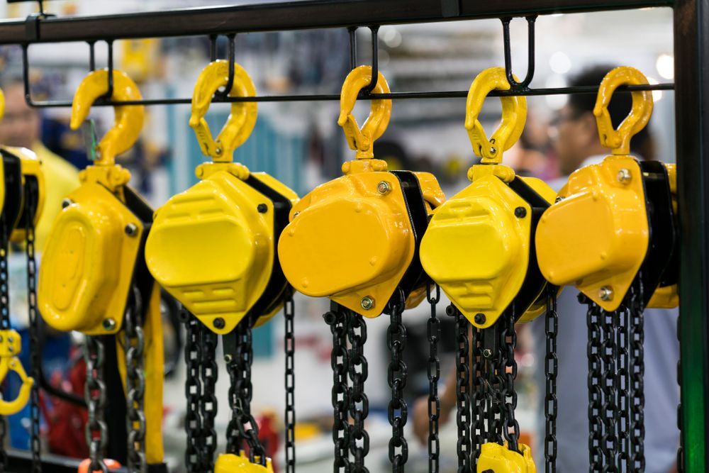 A Row of Bright Yellow Industrial Chain Hoists Hanging From a Metal Display Rack — Air & Lift Gear in Buderim, QLD