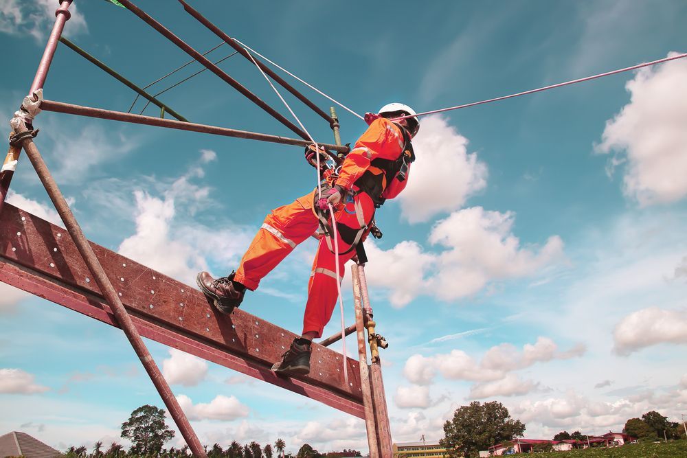 A Worker in a Bright Orange Jumpsuit and Safety Harness — Air & Lift Gear in Buderim, QLD