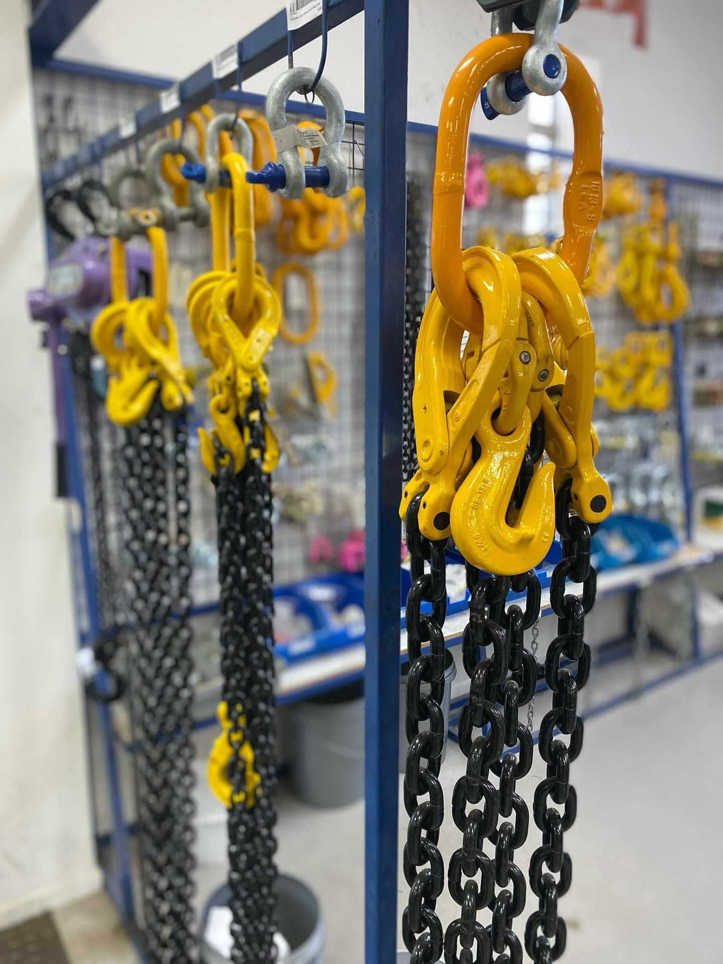 Rows Industrial Black Lifting Chains Yellow Hooks Hanging on Metal Racks — Air & Lift Gear in Buderim, QLD