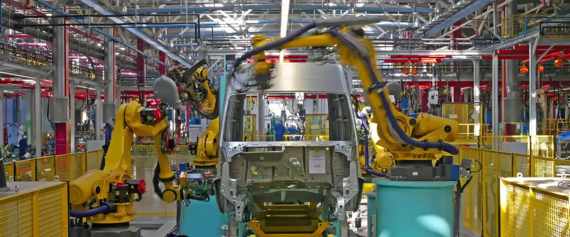 Car assembly line with yellow robotic arms working around a car body in a factory — Air & Lift Gear in Buderim, QLD