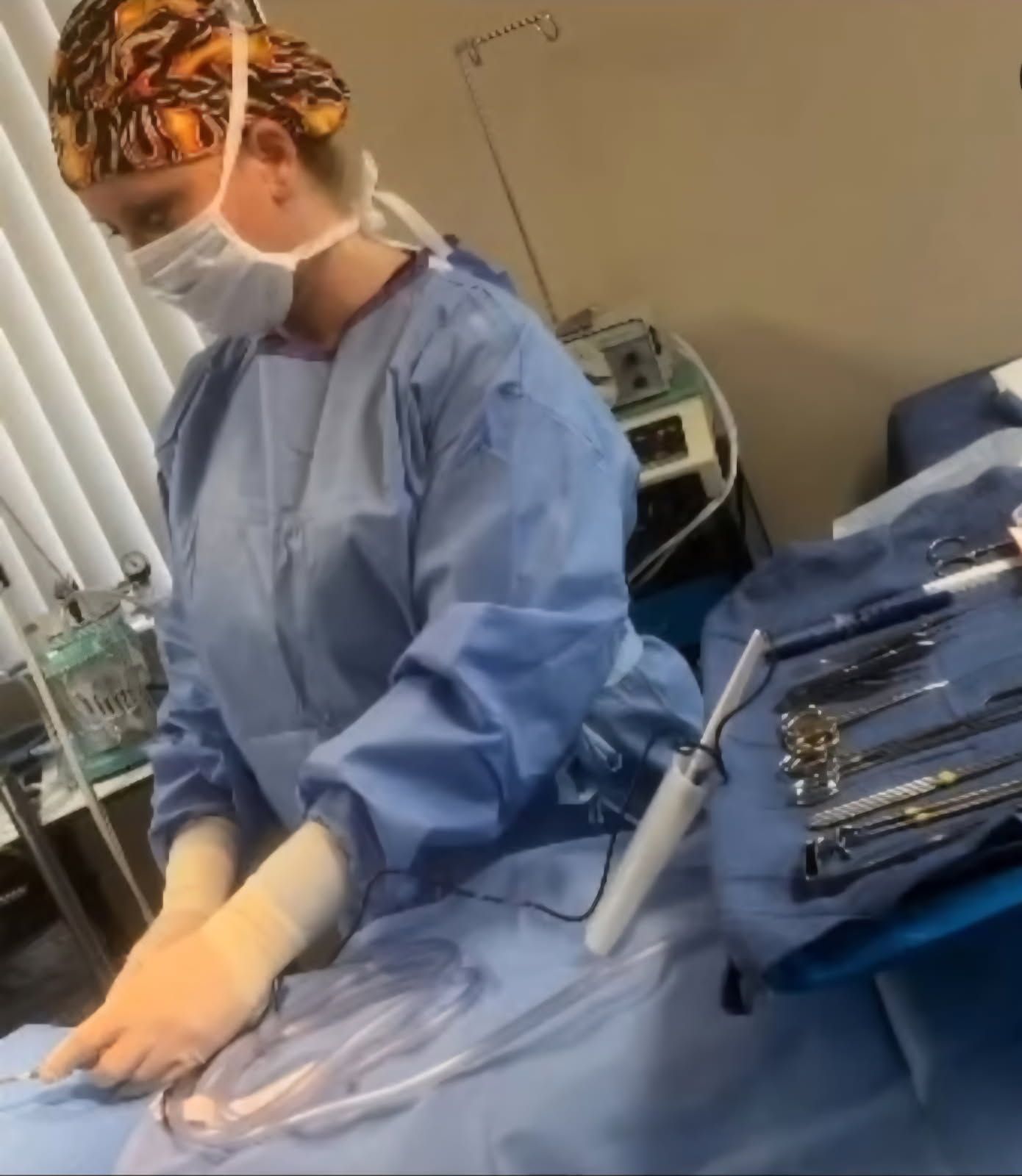Surgeon in blue scrubs and mask preparing instruments at a sterile operating table