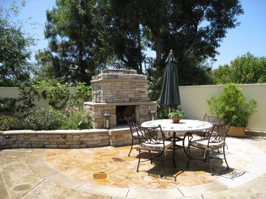 A patio with a table and chairs and a fireplace