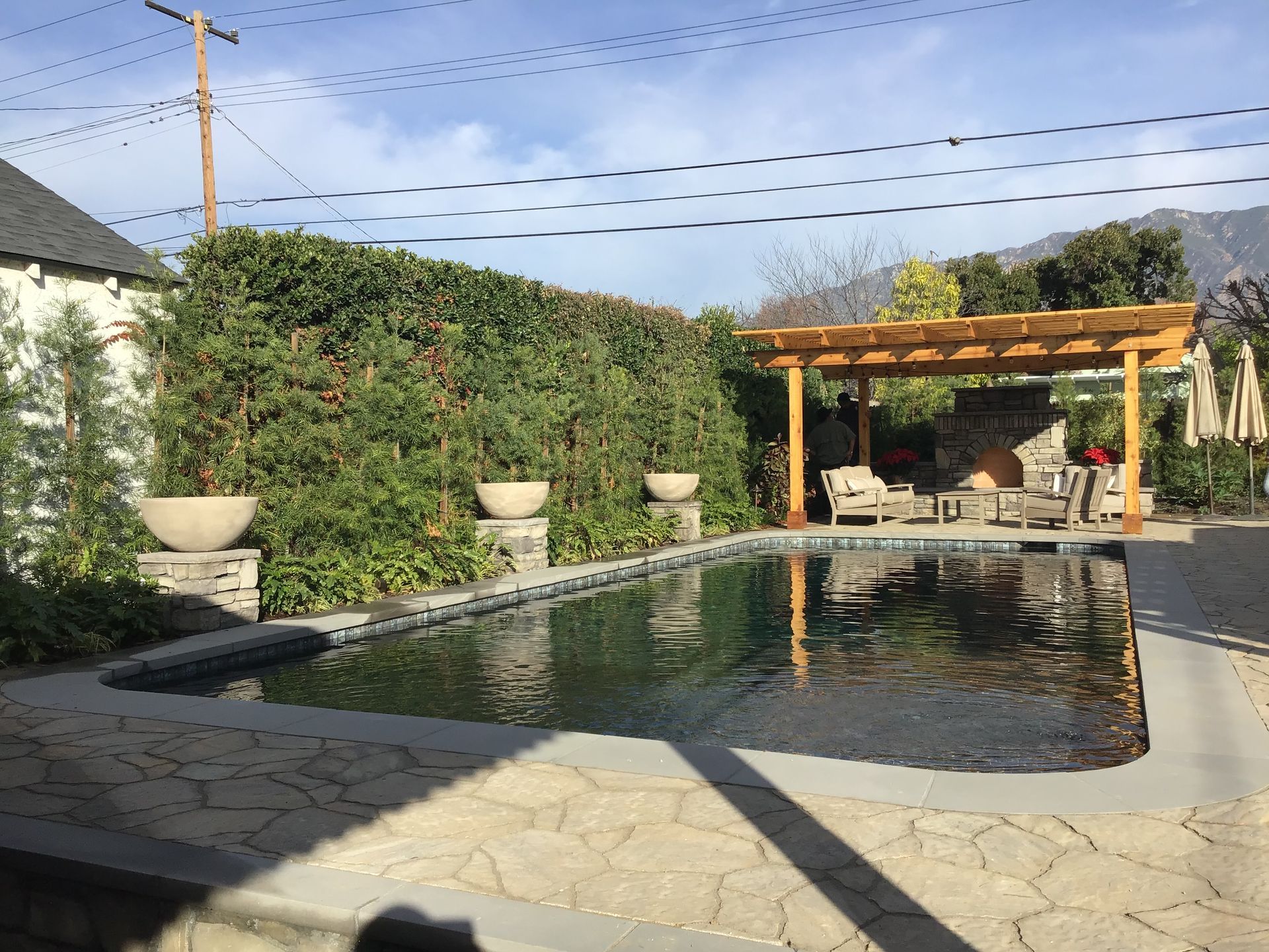 A large swimming pool with a pergola in the backyard