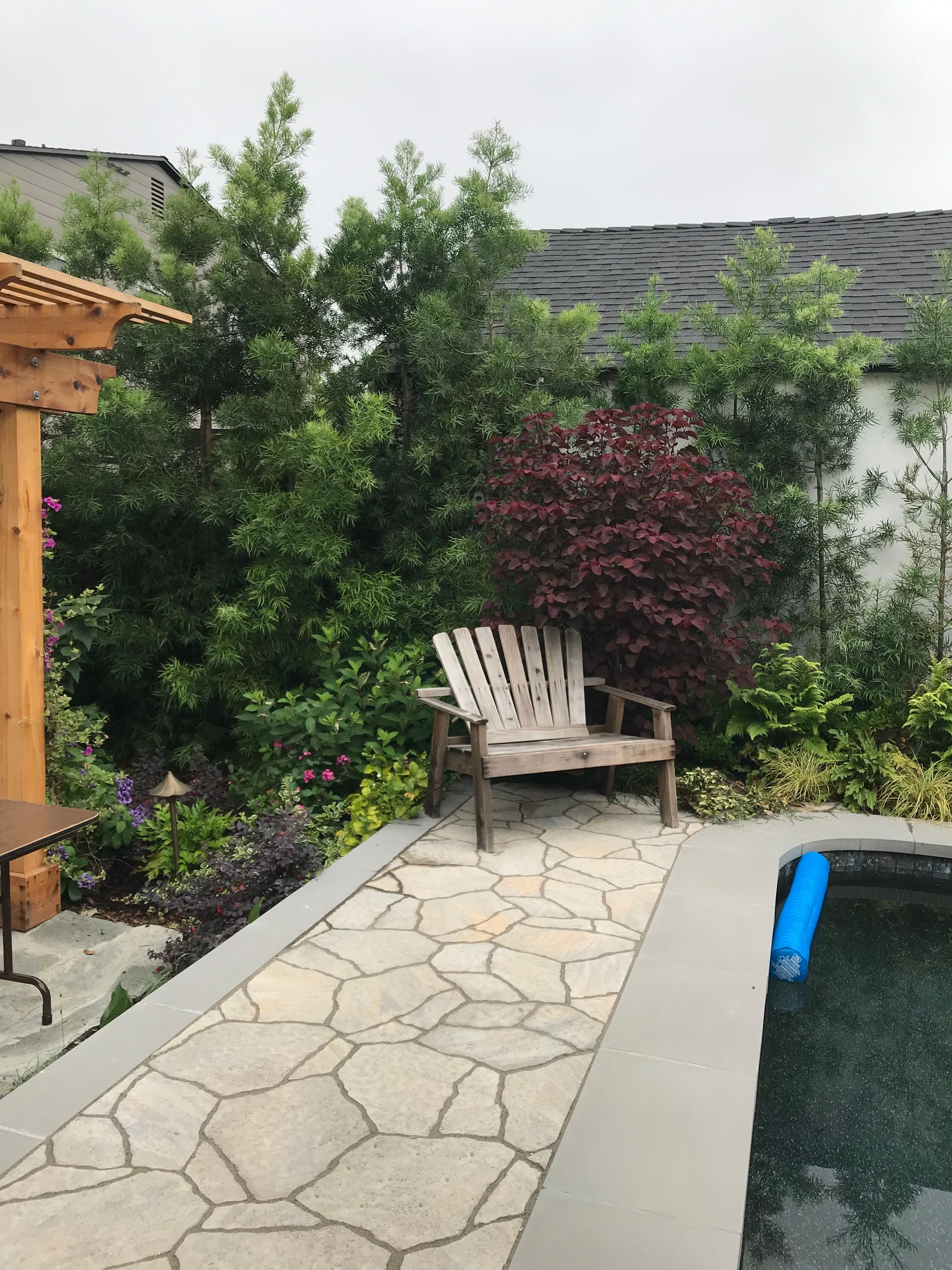 A wooden bench sits next to a swimming pool